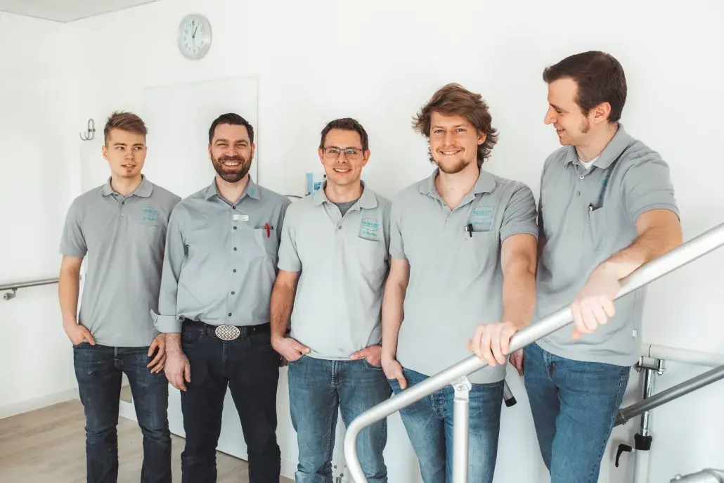Fünf Männer in grauen Poloshirts stehen in einem Sanitätshaus in Lüneburg.