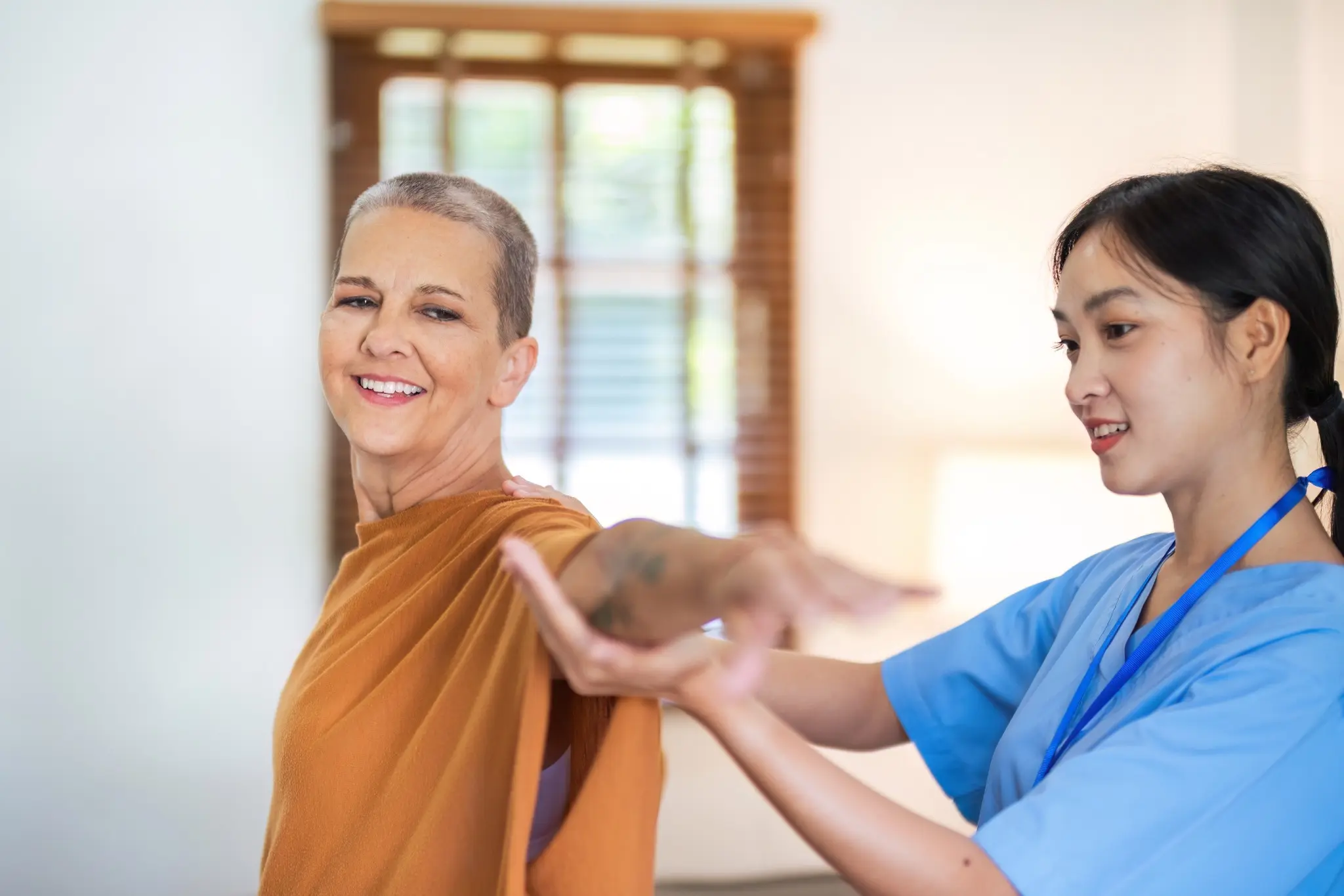 Eine Pflegerin hilft einer lächelnden Frau bei Physiotherapie-Übungen im Sanitätshaus.