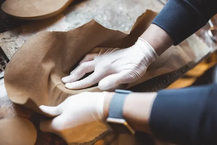 Hände formen in einer Orthopädietechnik-Werkstatt Leder für orthopädische Einlagen.