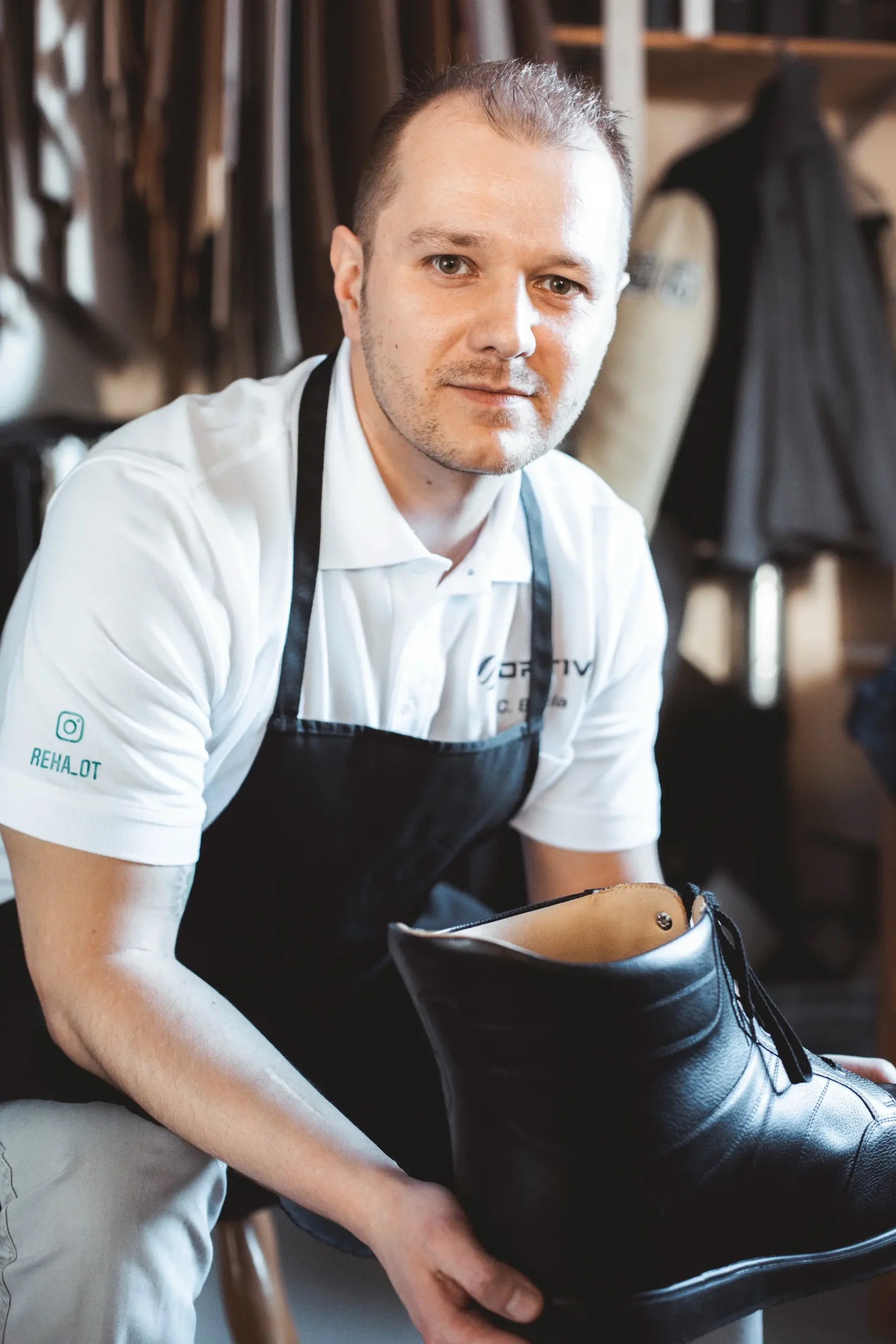 Ein Mann hält in einer Werkstatt einen orthopädischen Schuh in der Hand.