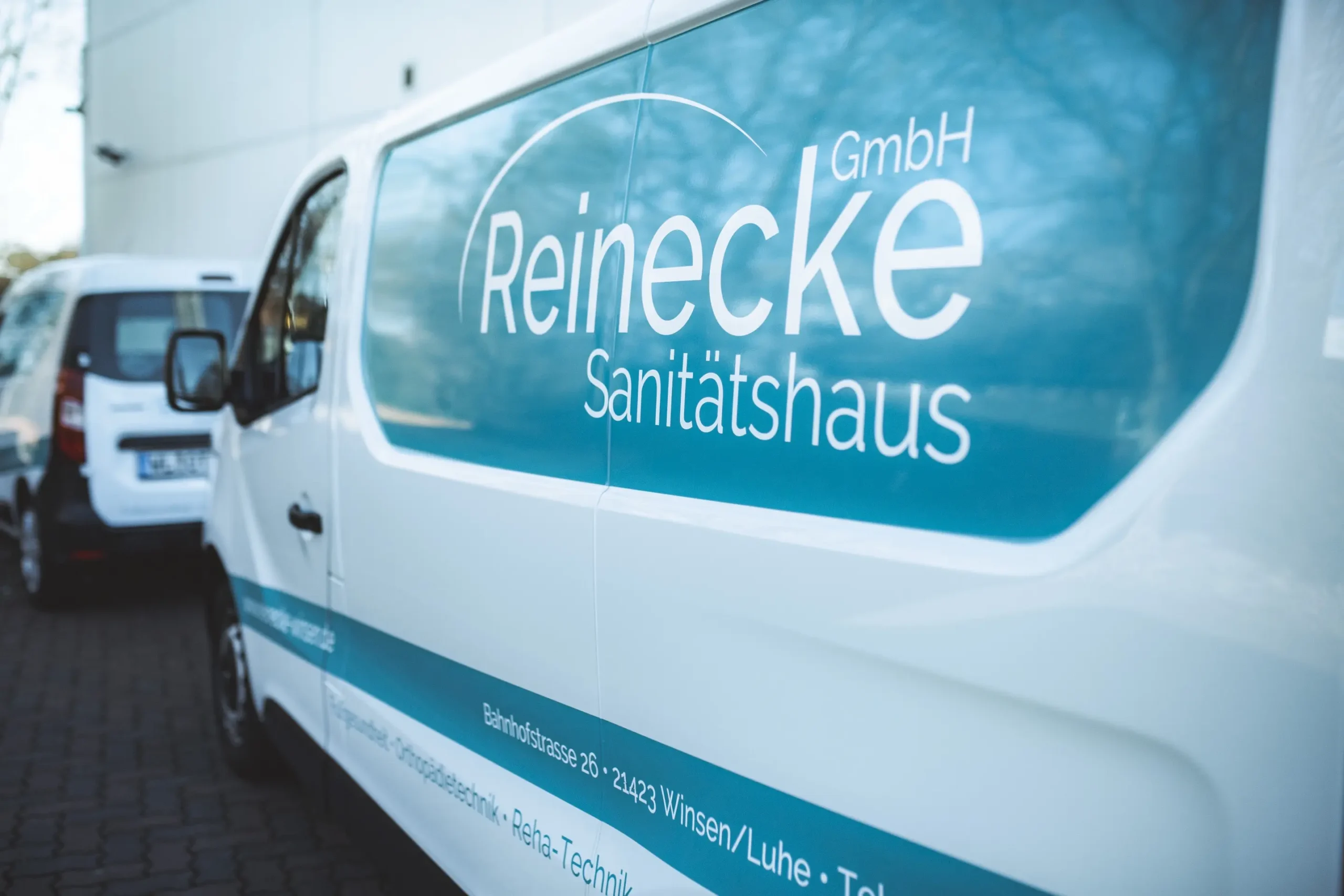 Ein Firmenwagen vom Sanitätshaus Reinecke parkt vor einem Gebäude.