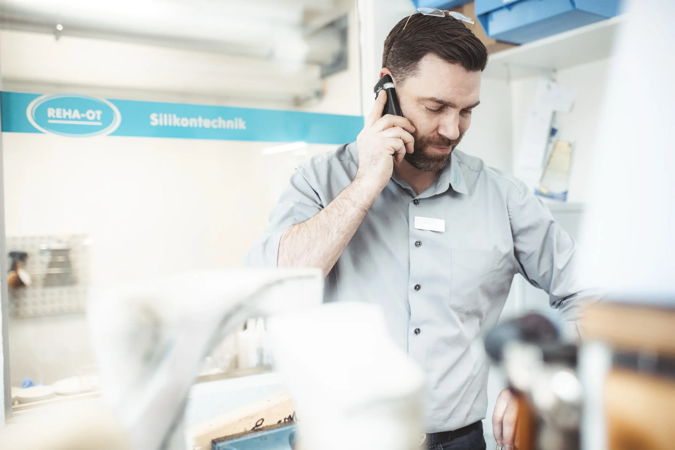 Mitarbeiter von REHA-OT telefoniert in der Orthopädietechnik-Werkstatt.