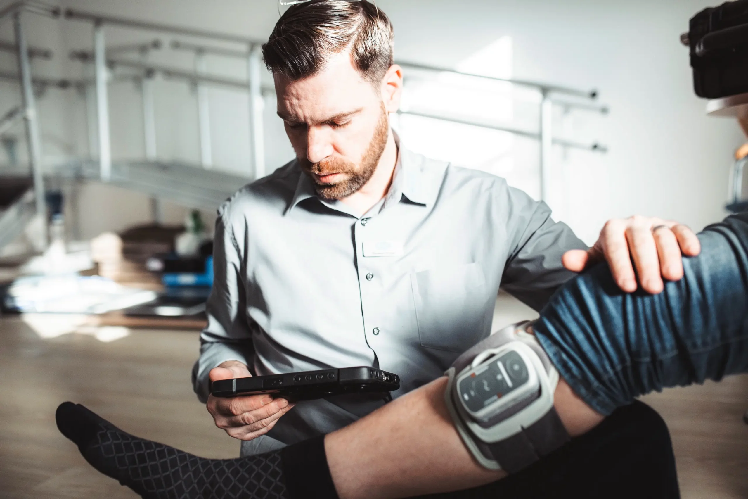 Ein Mann überprüft eine Knieorthese mit einem digitalen Gerät in einer orthopädietechnischen Werkstatt.