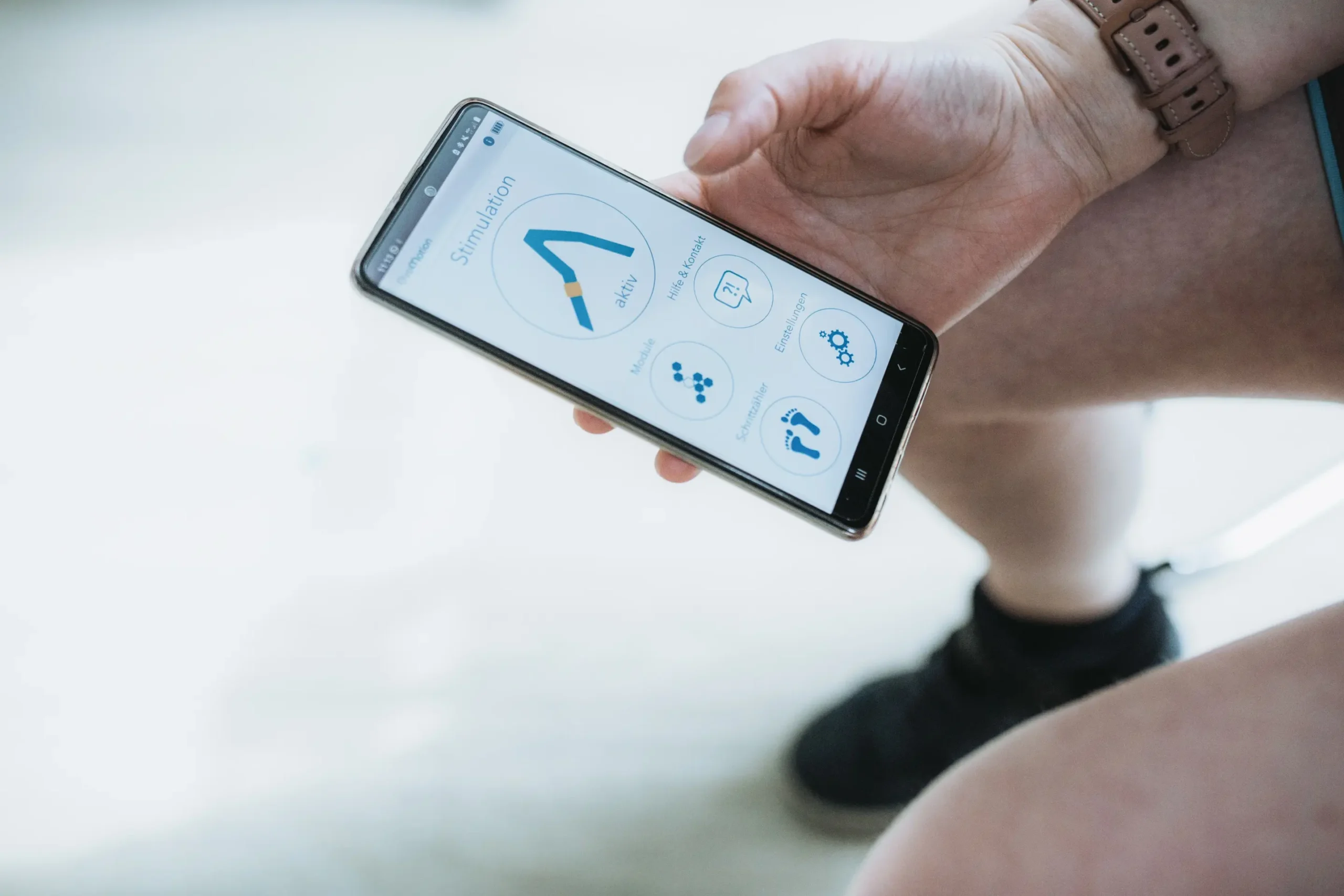 Eine Person hält ein Smartphone mit einer App für Bewegungsanalyse.