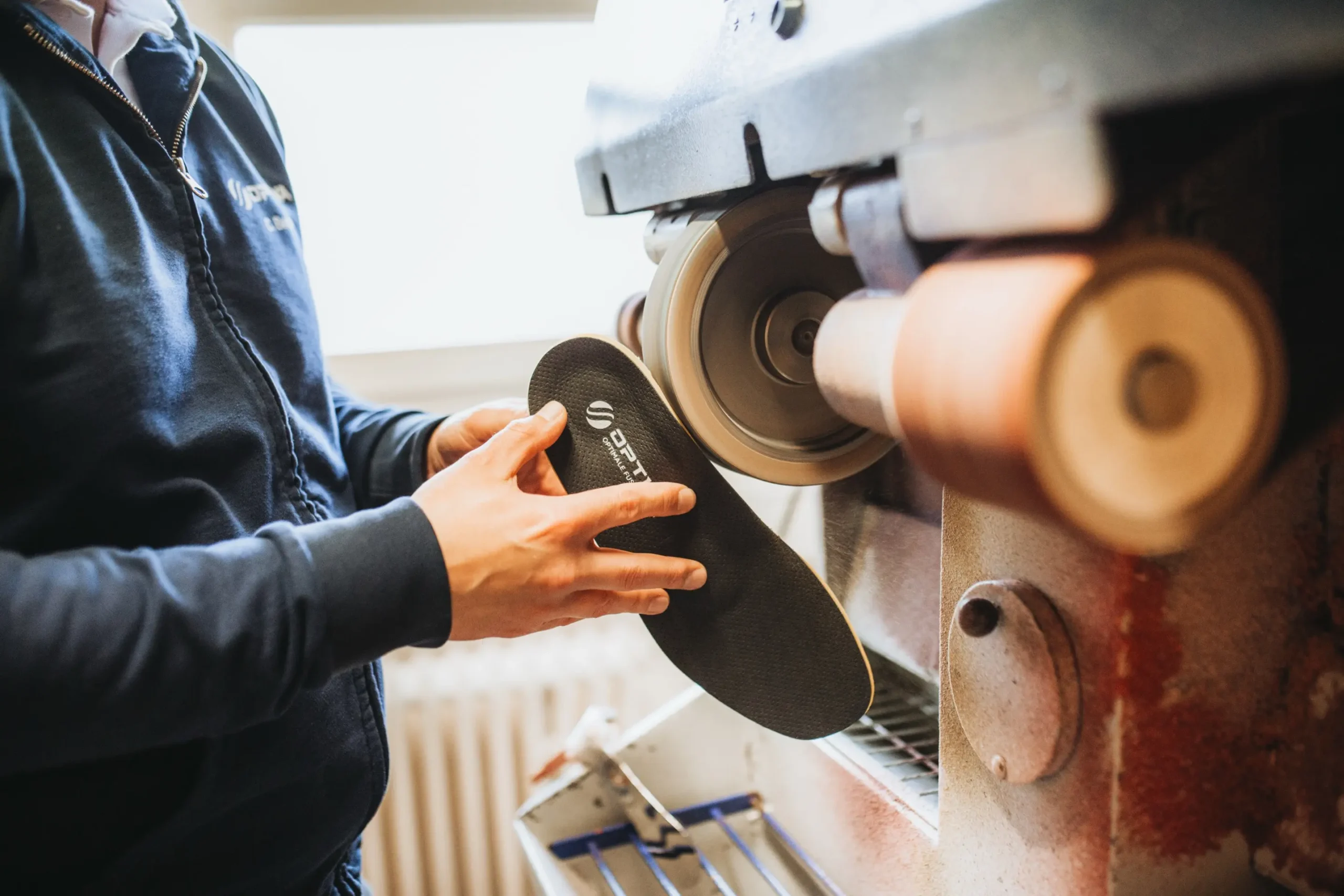 Ein Orthopädieschuhmacher bearbeitet eine Einlage in einer Orthopädietechnik-Werkstatt.