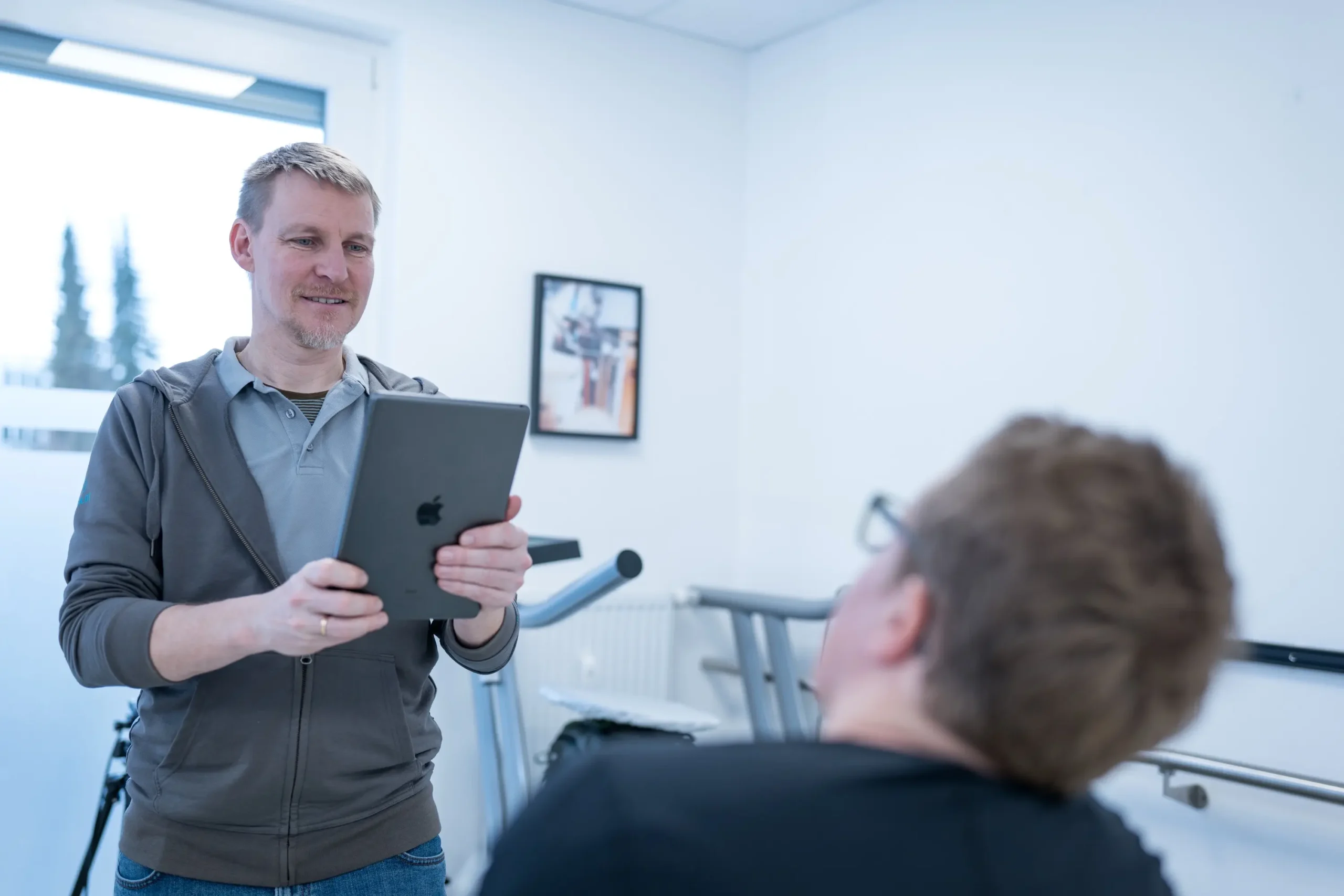 Ein Mann hält ein Tablet, während er mit einer Person in einem Sanitätshaus interagiert.
