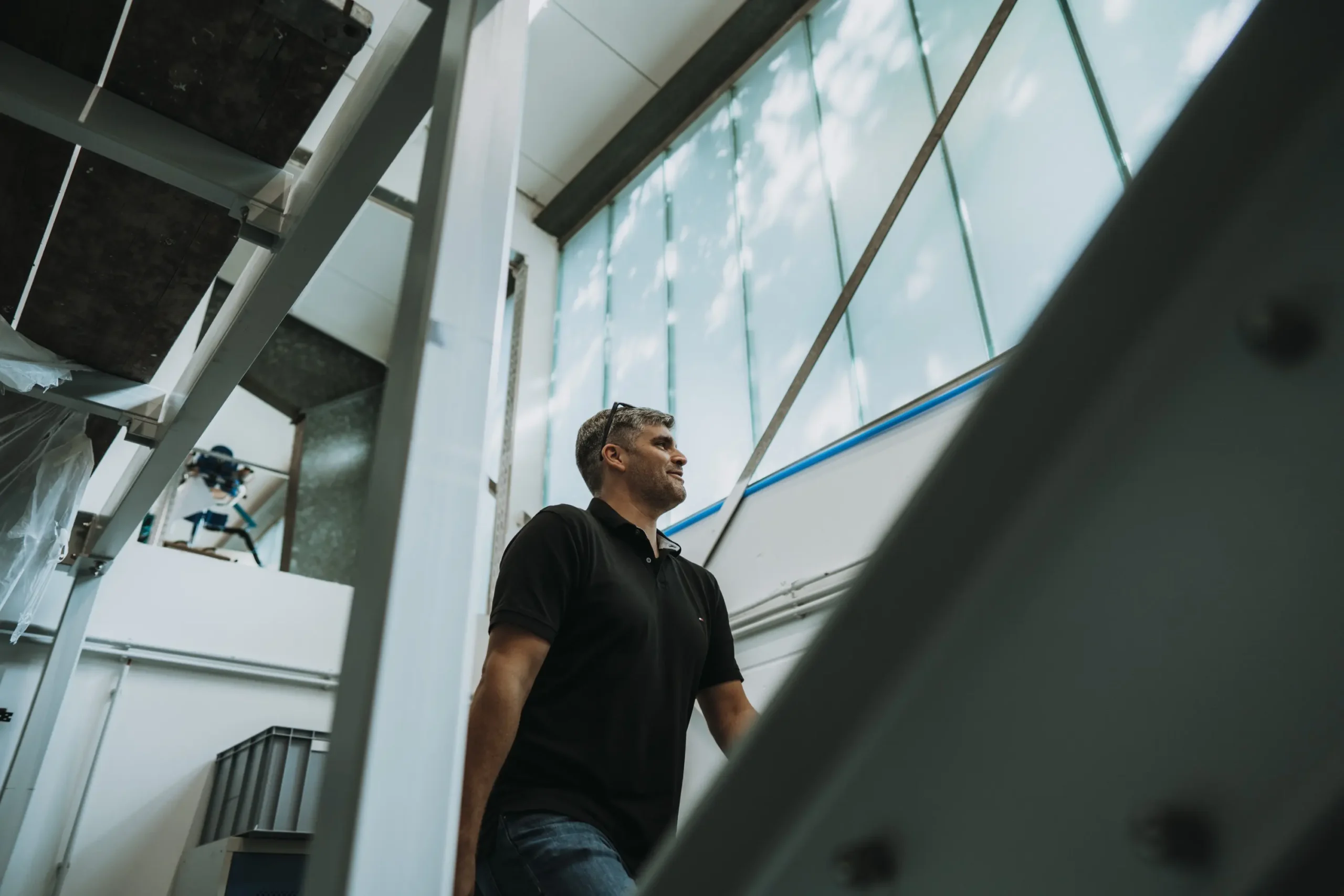Person im schwarzen Shirt in einem modernen Gebäude mit großen Fenstern.