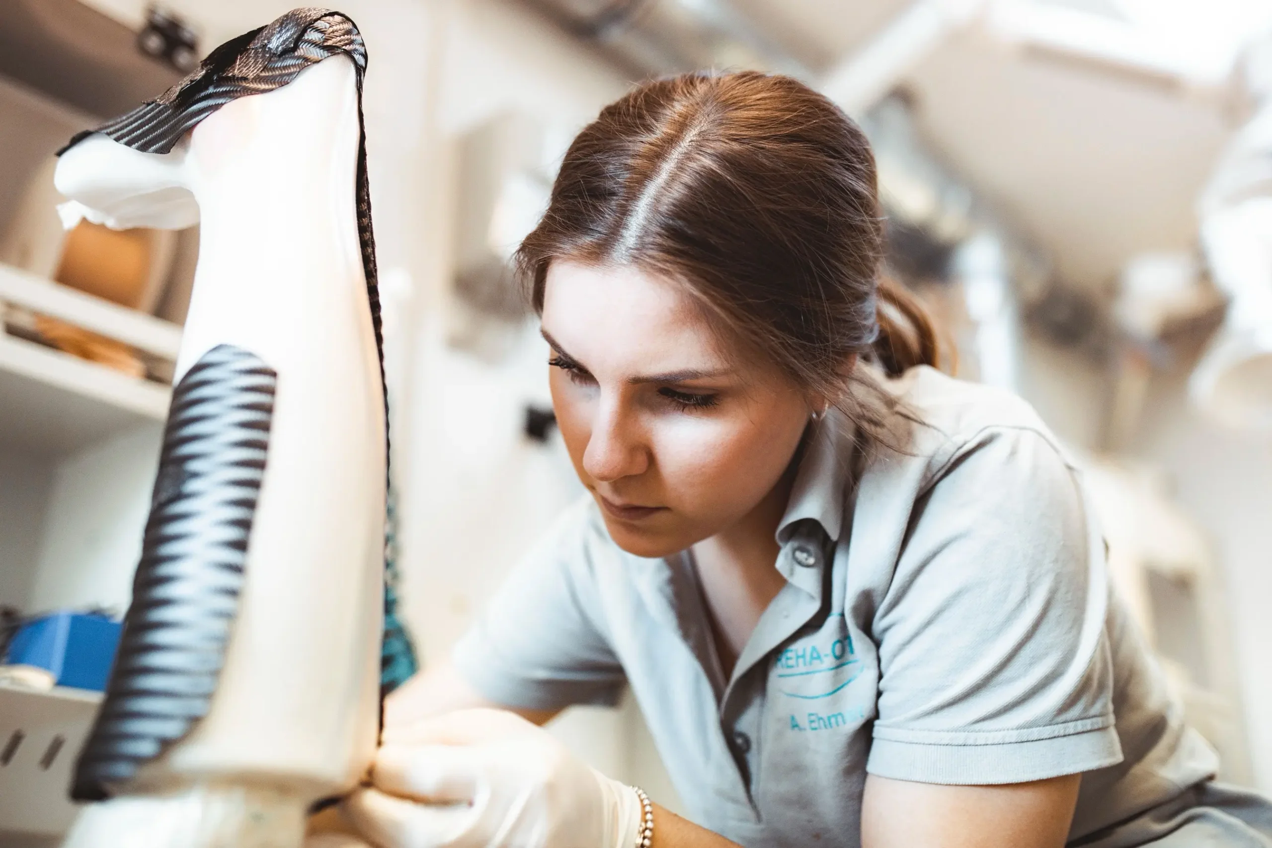Eine Frau arbeitet konzentriert an einer Beinprothese in einer Orthopädietechnik-Werkstatt.