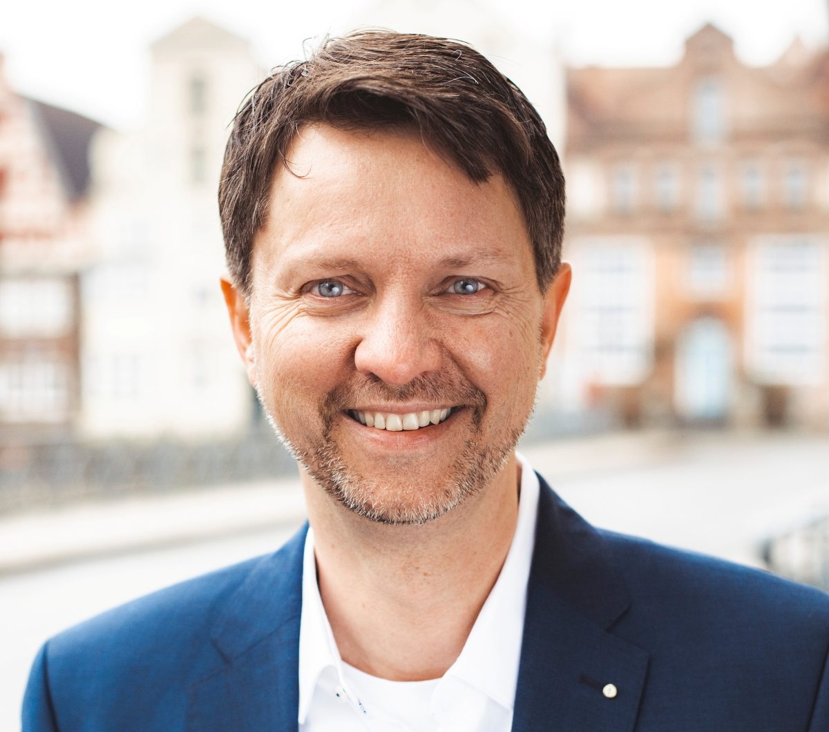 Ein Mann im blauen Anzug lächelt in die Kamera